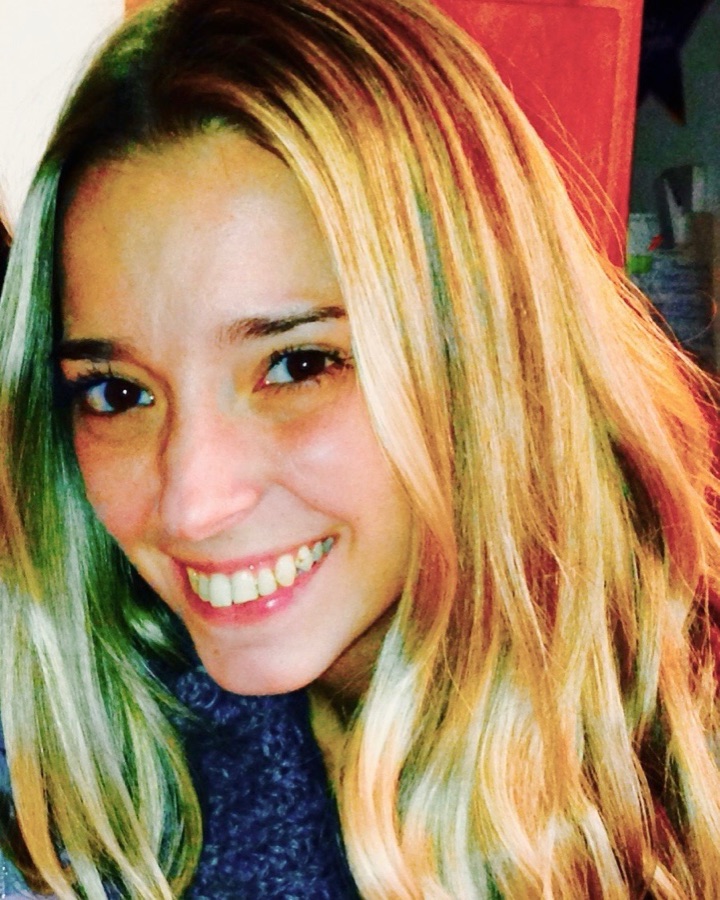 Brittney smiling, her long blonde hair falling over a blue knit scarf