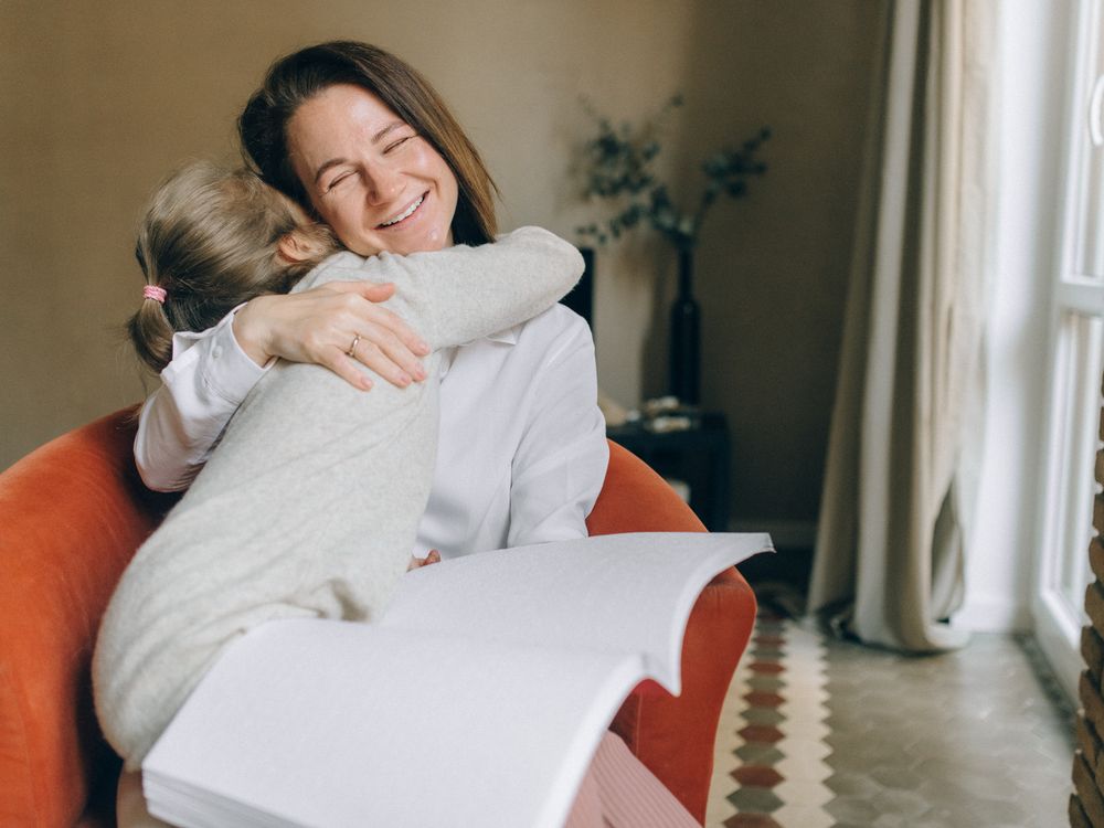 A smiling mother wrapped in a hug from her young daughter